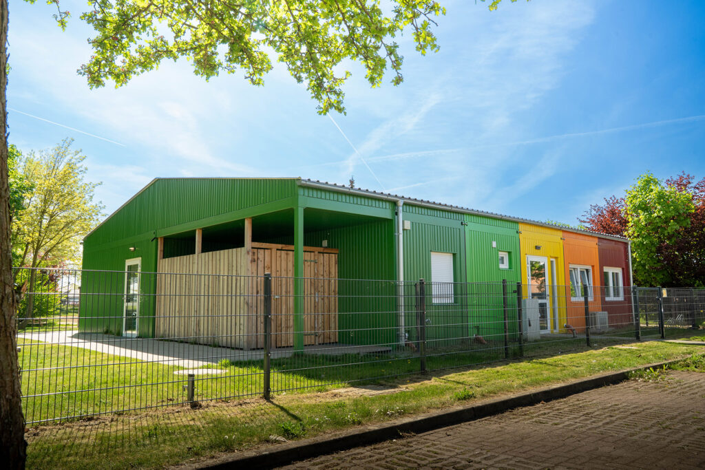 Aussenansicht einer hellen bunten freundlichen Kita aus Container