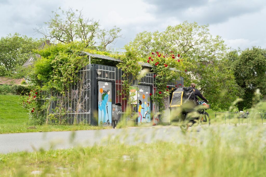 Öffentlicher WC-Container für die Bremer Stadtreinigung an der Weser Frontalansicht mit Radfahrer