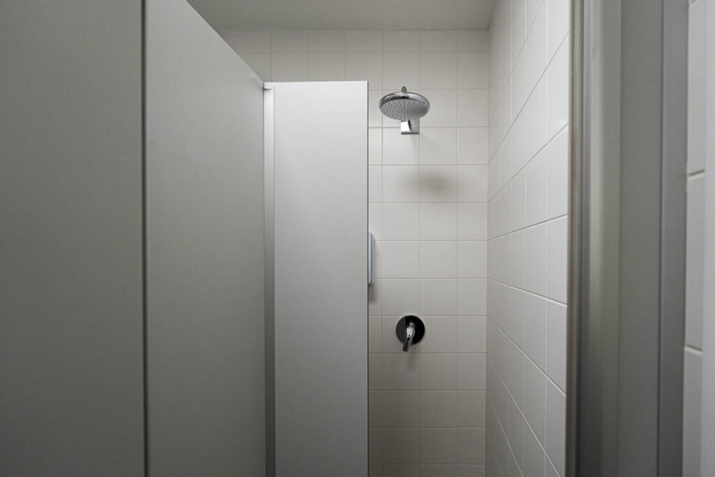 Dusche mit Trennwand, gefliesten Wänden und Unterputzarmaturen