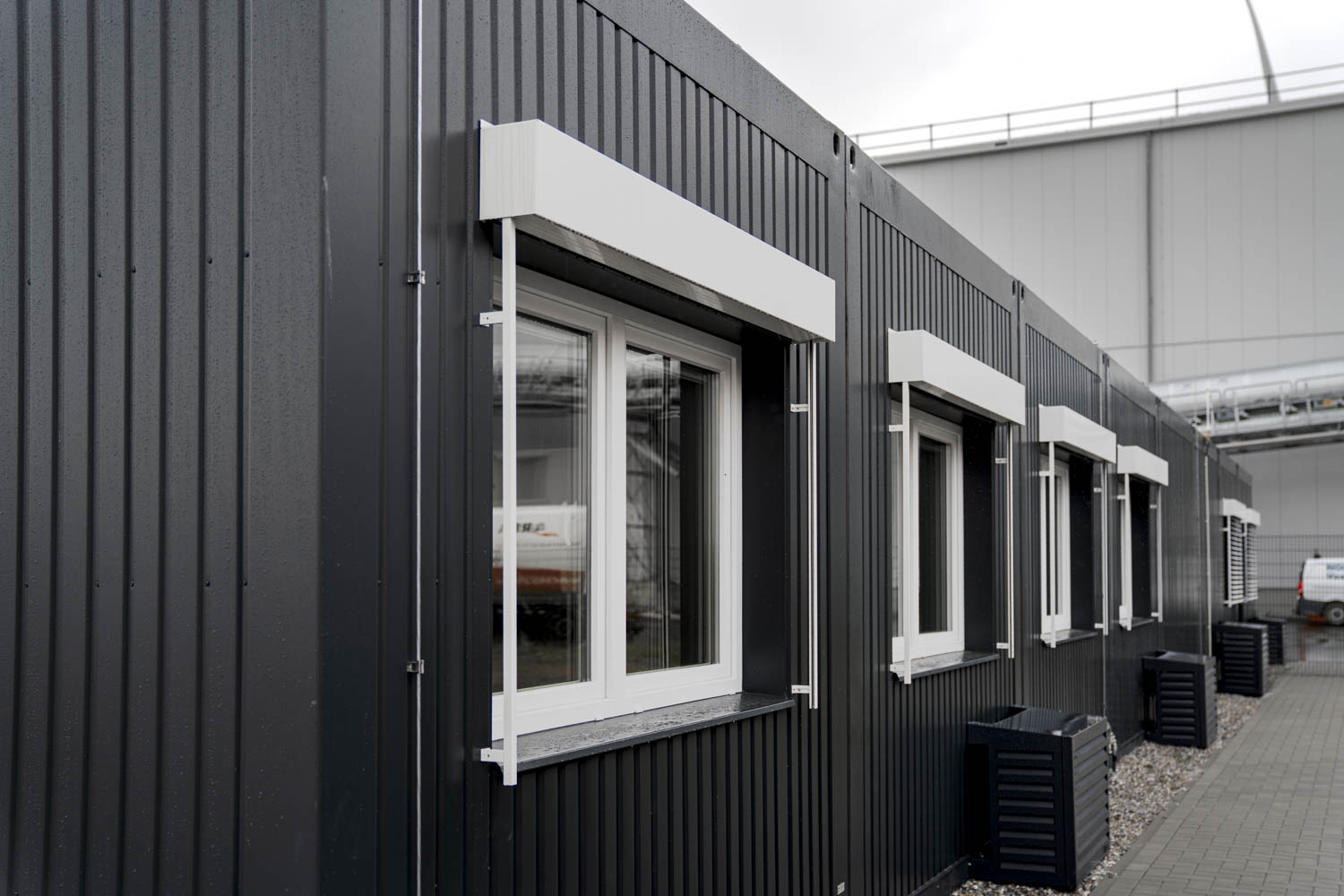 Außensicht der Bürocontaineranlage für EEW: Fassade in anthrazitgrau, Fenster mit Raffstores und Verkleidung der Klimageräte