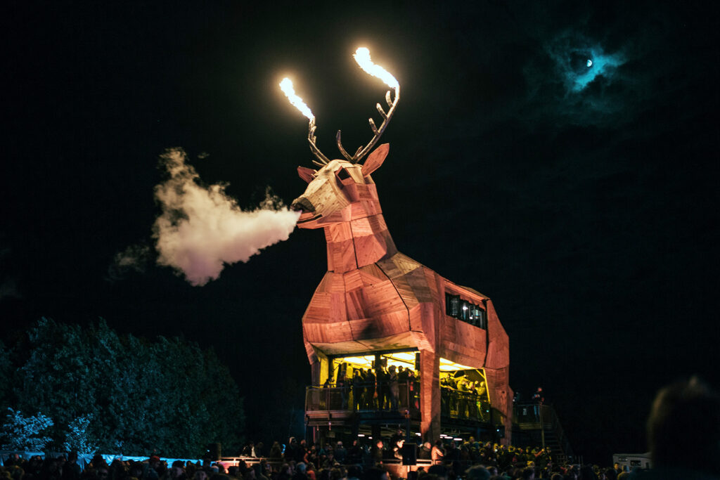 Beleuchteter Jägermeister Platzhirsch mit Flammen am Geweih und Rauch aus der Nase bei Nacht