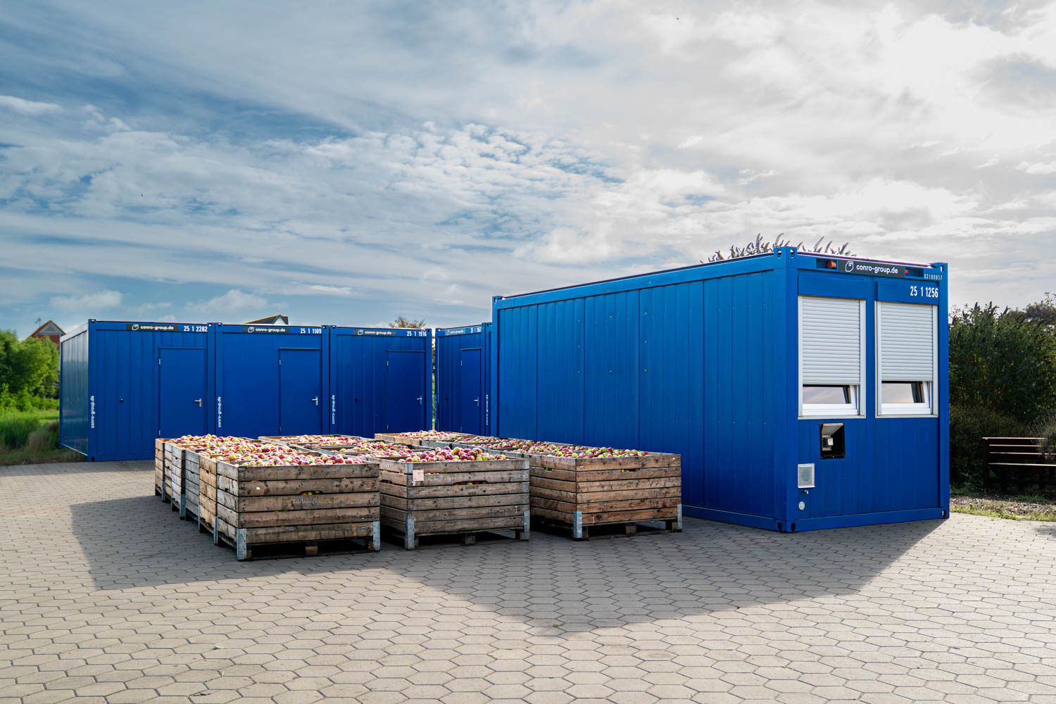 Mietcontaineranlage auf einem Obsthof im Alten Land während der Apfelernte als Unterkunft für die Erntehelfer vor Kisten mit Äpfeln