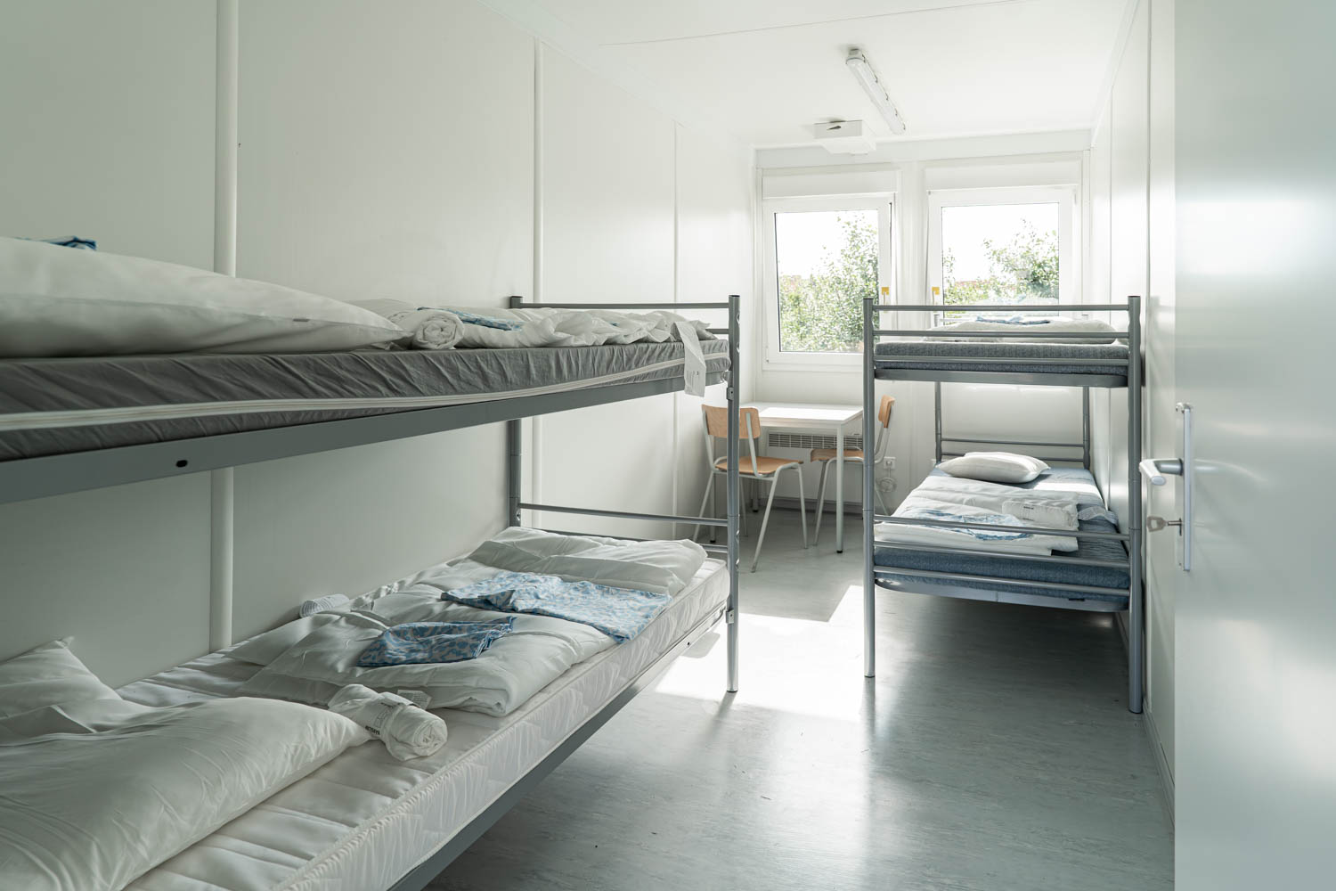 Innenansicht in einen Mietcontainer BM2 als Unterkunft für die Erntehelfer auf einem Obsthof im Alten Land während der Apfelernte mit 2 Etagenbetten und Tisch und Stühle