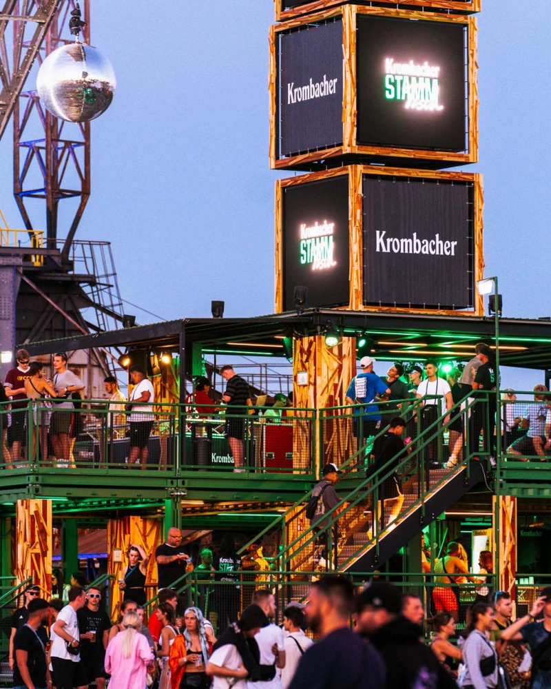 Beleuchteter Barcontainer in Abendstimmung mit Publikumsverkehr